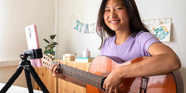 Woman with guitar and laptop writing music